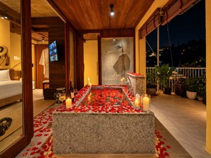 Una habitación con un banco de piedra, velas y pétalos de rosa.