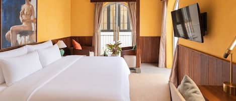 A hotel room with a large bed, a television mounted on the wall, and a window with curtains.