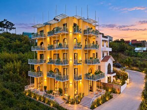 A multi-story hotel with balconies, a central courtyard, and a surrounding landscape. - Nexus House An Son Da Lat (Xuan Huong - Da Lat)