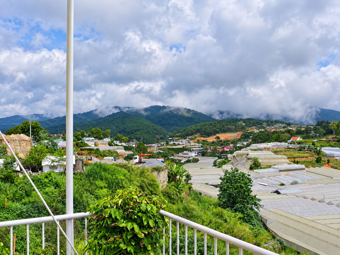 A rural landscape with a view of a village and mountains in the distance.