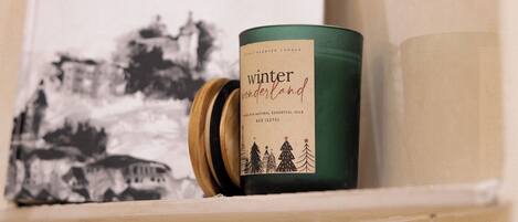 A candle with a label, a book titled "DÂLÂT DAO BUÔC NGHÊ THUẬT," and a wall with a black and white illustration.