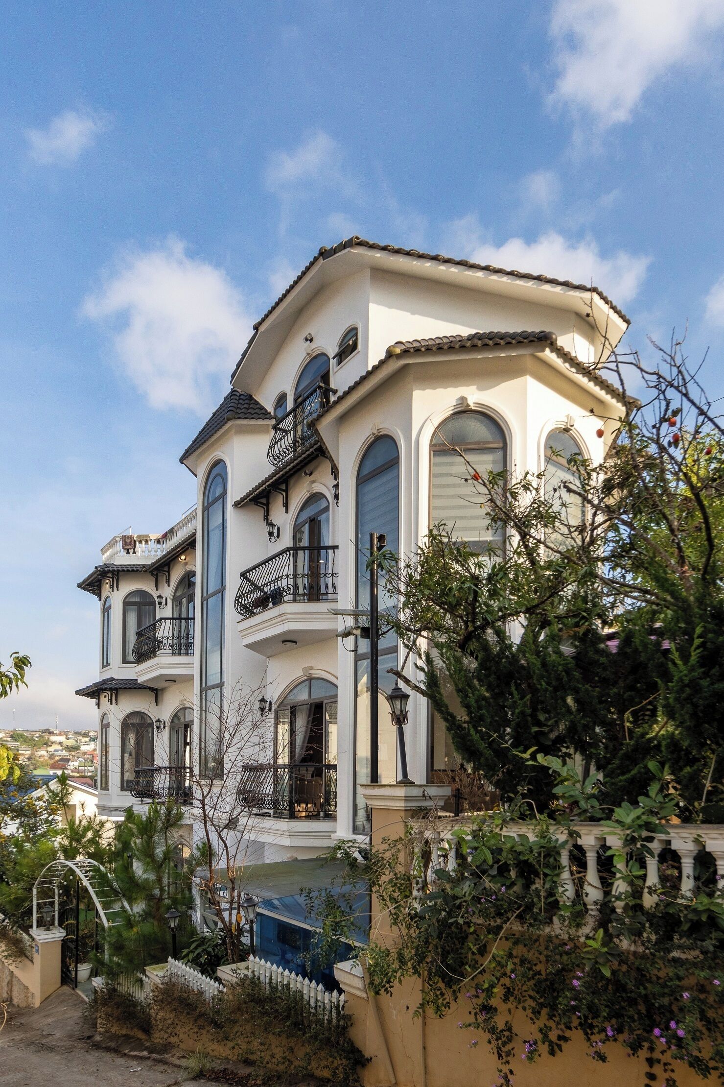 Un edificio de varios pisos con balcones, ventanas grandes y fachada blanca.