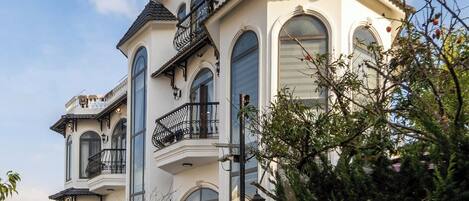 Un edificio de varios pisos con balcones, ventanas grandes y fachada blanca.