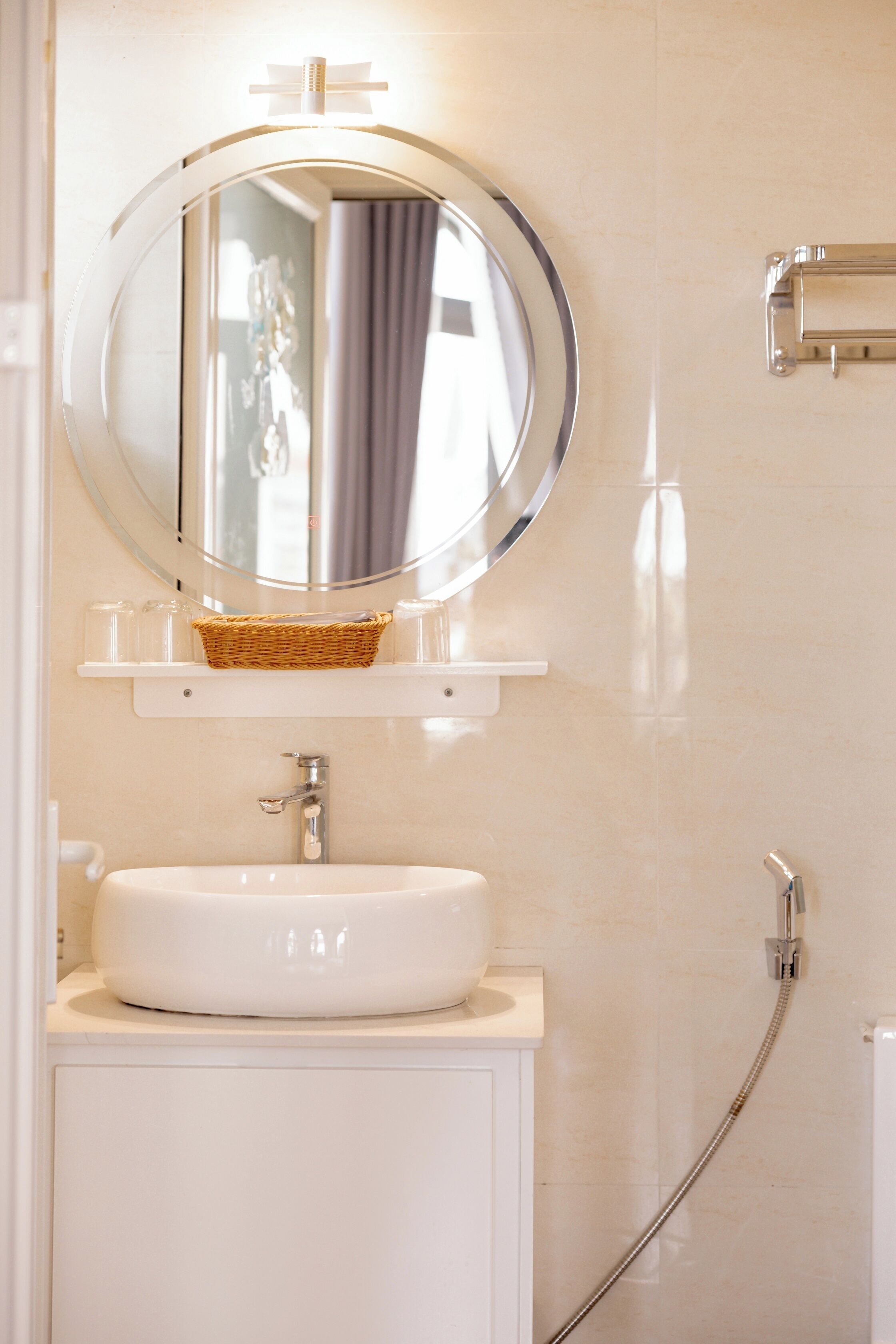 Een badkamer met een ronde spiegel, een witte wastafel en een douche.