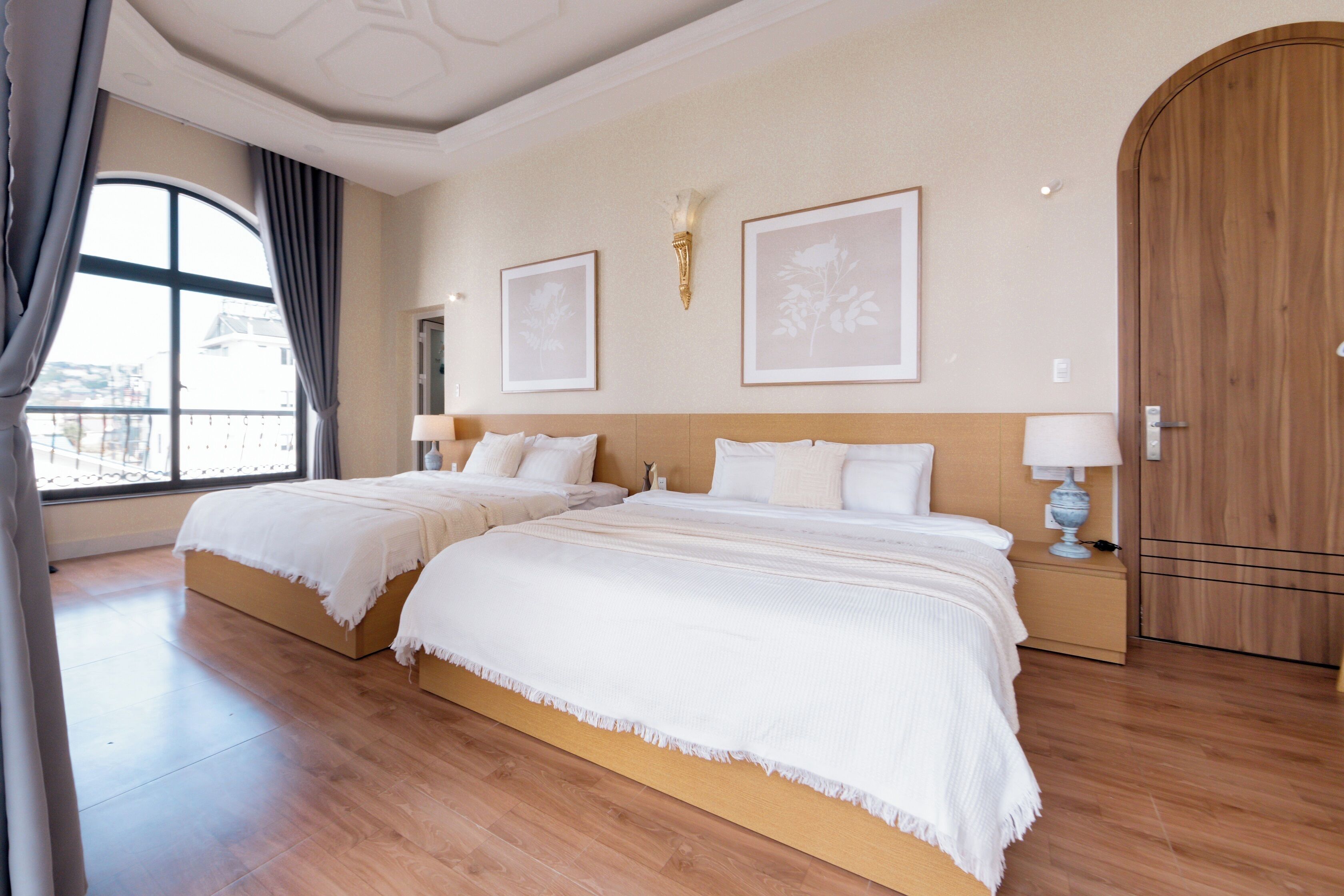 Une chambre d’hôtel avec deux lits, une grande fenêtre et une porte en bois.
