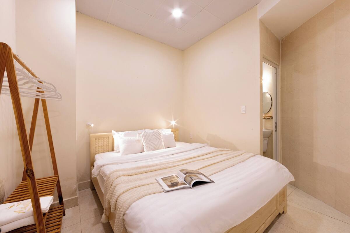 Een slaapkamer met een bed, een houten kleerhanger en een tijdschrift op het bed.