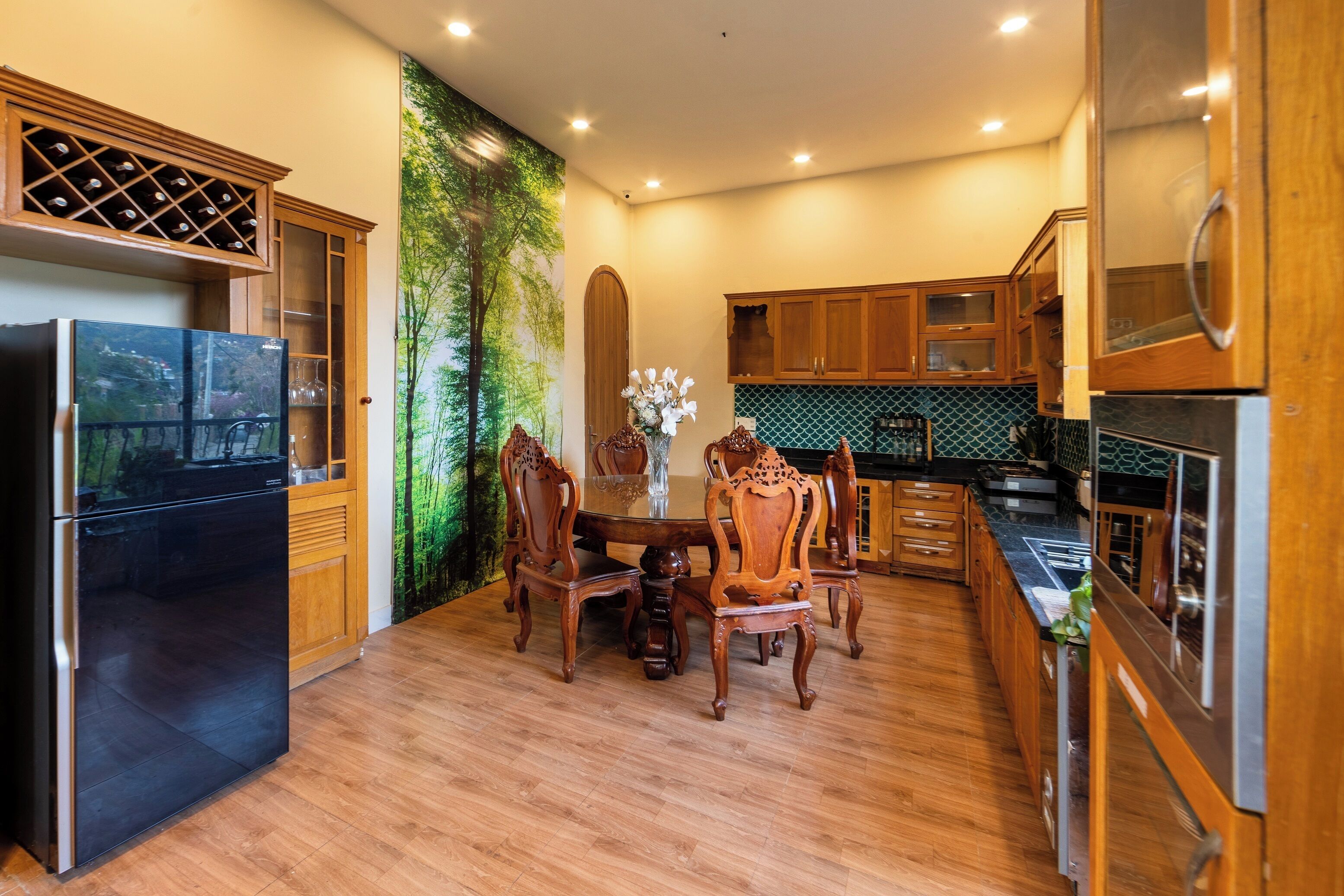 A modern kitchen with wooden cabinets, a black refrigerator, and a dining table with chairs.
