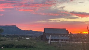 A rural landscape with a barn and greenhouse structures.