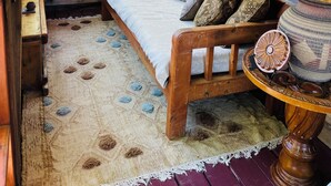Ein gemütliches Schlafzimmer in einer Blockhütte mit einem Bett, Kissen, einem Teppich und einer Lampe.