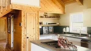 Eine geräumige Küche mit Holzbalken, einer zentralen Kochinsel und einem Fenster für natürliches Licht.