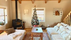 Ein gemütliches Wohnzimmer mit Holzboden, Kamin, Weihnachtsbaum und zwei weißen Sofas.
