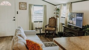 A cozy living room with a sofa, a chair, a television, and a small table.