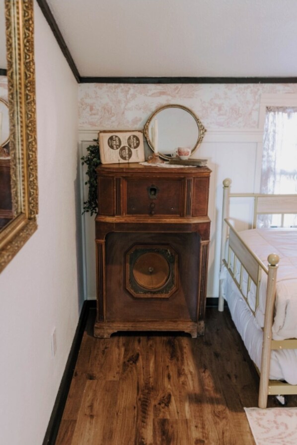 A bedroom with a wooden dresser, a bed, and a mirror.