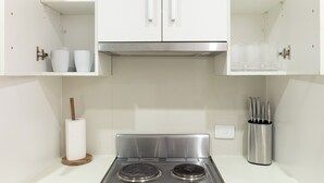 Une cuisine avec des meubles blancs, une cuisinière en acier inoxydable et un bloc à couteaux.