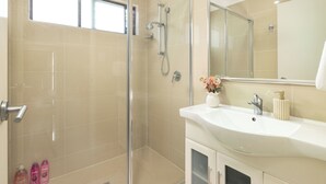 A modern bathroom with a glass-enclosed shower, a white sink, and a large mirror. - Smart Suites Self Check-in Apartments - 18 Darnley (Rocklea)