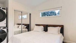 Ein Schlafzimmer mit Bett, Fenster und Waschmaschine.