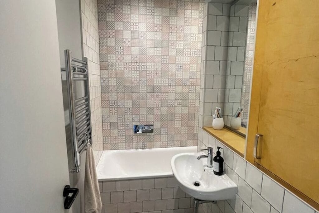 Ein Badezimmer mit einer weißen Badewanne, einem Waschbecken mit Seifenspender und einem Spiegel darüber.