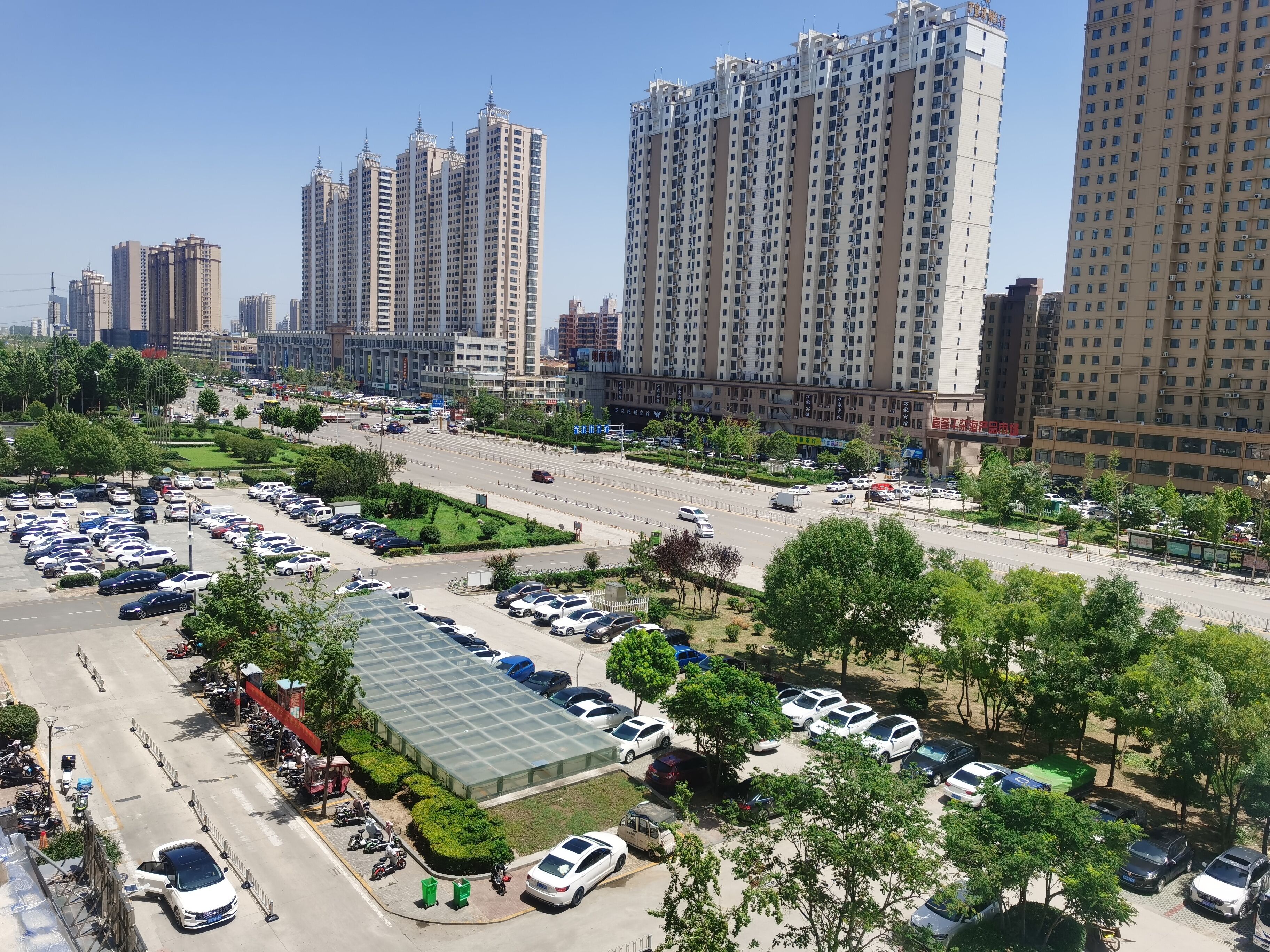 A parking lot with multiple cars and a green-roofed building.