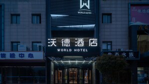 Un hotel con un llamativo letrero que dice 'WORLD HOTEL', con un diseño moderno, ventanas iluminadas y una pantalla digital.