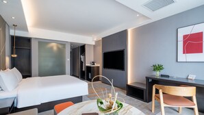 Una habitación de hotel moderna con una cama grande, un escritorio, una silla y un televisor en la pared.