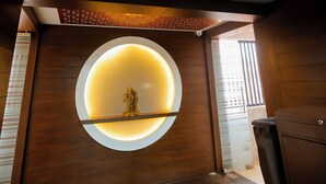 A modern interior with a circular illuminated wall, wooden paneling, and a ceiling with geometric patterns. - Hotel Mukut Mani Govardhan (Mathura)