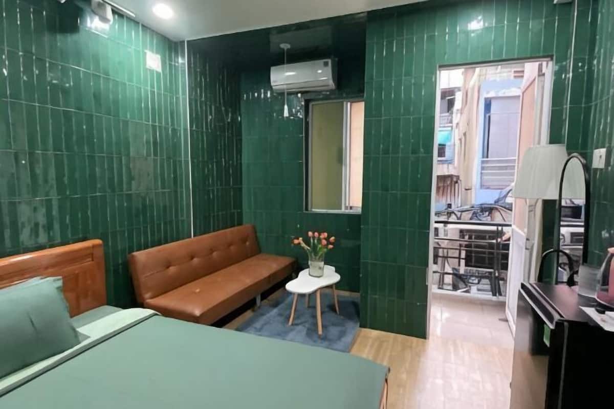 Une pièce comprenant un lit, un canapé, une petite table avec des fleurs, un miroir et une fenêtre.