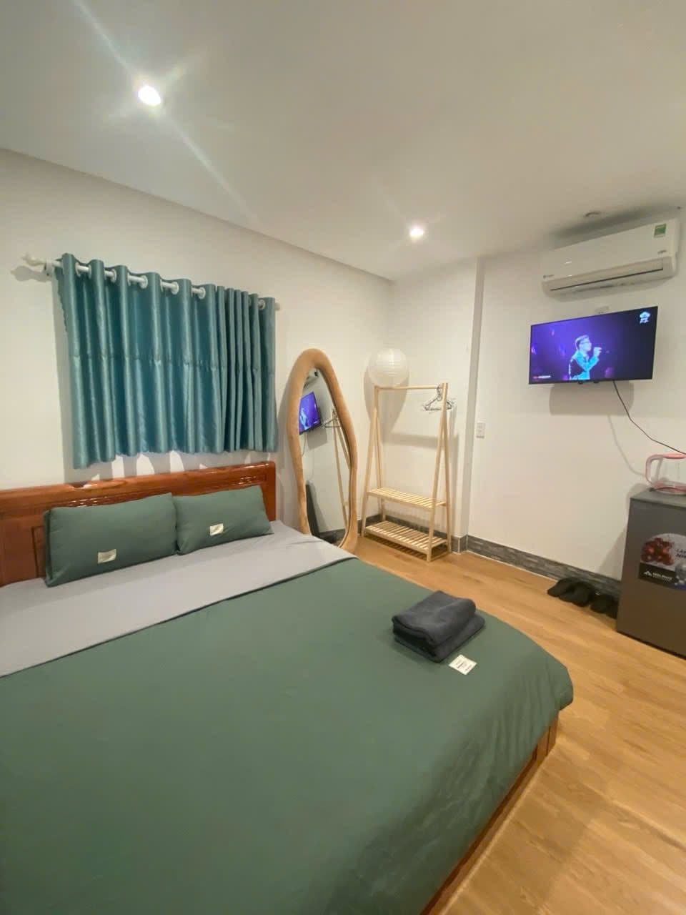 Ein Hotelzimmer mit Bett, Fernseher, Holzstuhl und kleinem Tisch.