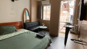 Une chambre d’hôtel comprenant un lit, un canapé, une petite table, un appareil de climatisation, une télévision et un balcon avec vue.