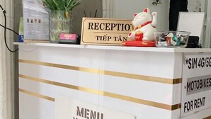 Un comptoir d’accueil avec un menu proposant les différentes variétés de café « Meow », un panneau indiquant la réception, et une statuette décorative de chat.