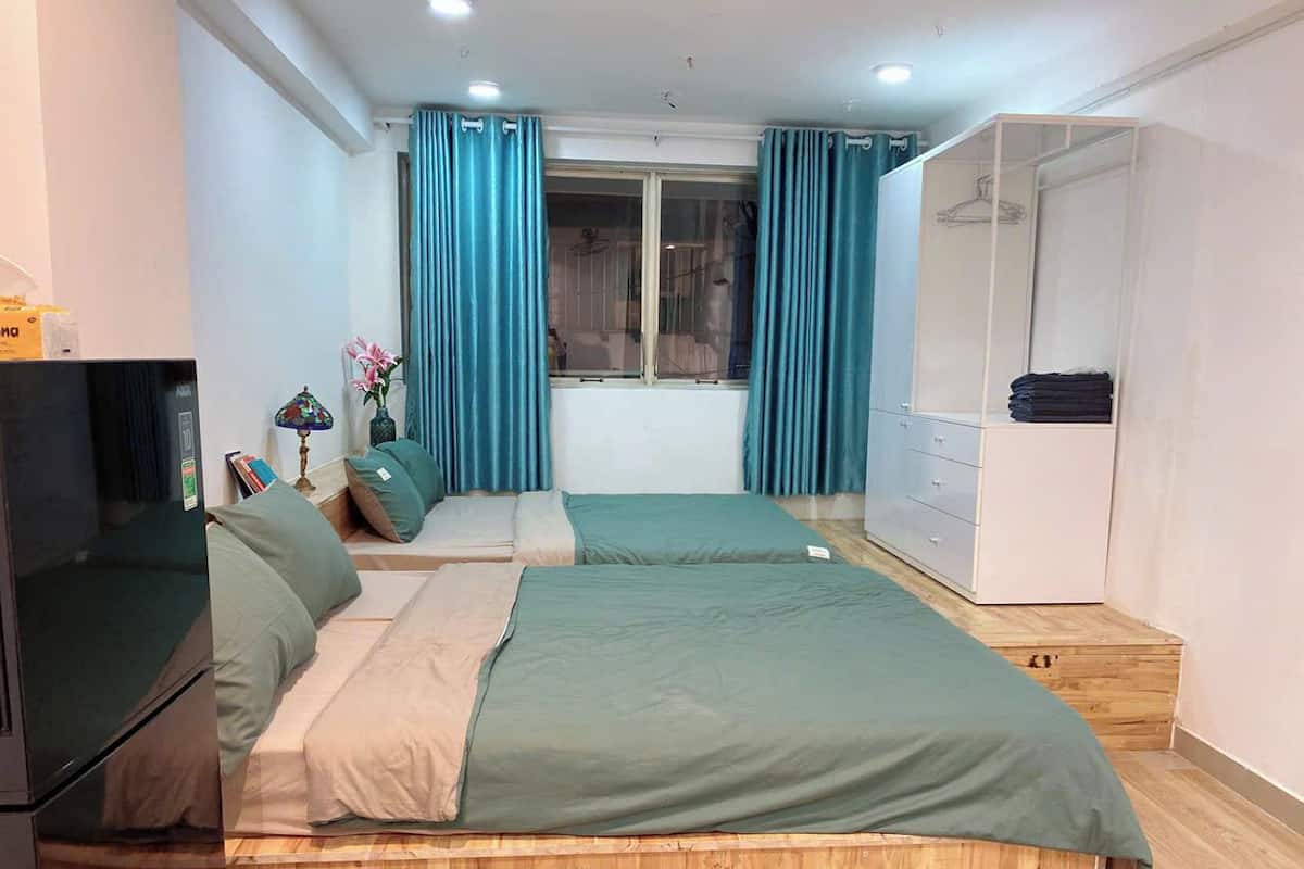 Une chambre avec deux lits, une armoire, une télévision et une fenêtre avec des rideaux.
