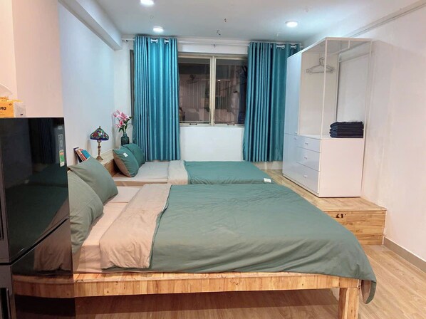Quarto com duas camas, guarda-roupa, televisão e janela com cortinas.
