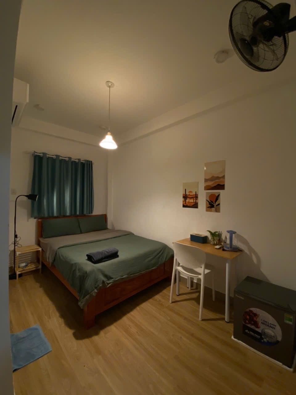 A bedroom with a bed, desk, chair, and a ceiling fan.