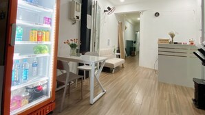 Un espace d’accueil comprenant un réfrigérateur rempli de boissons, un comptoir de réception et un coin salon avec une table et des chaises.