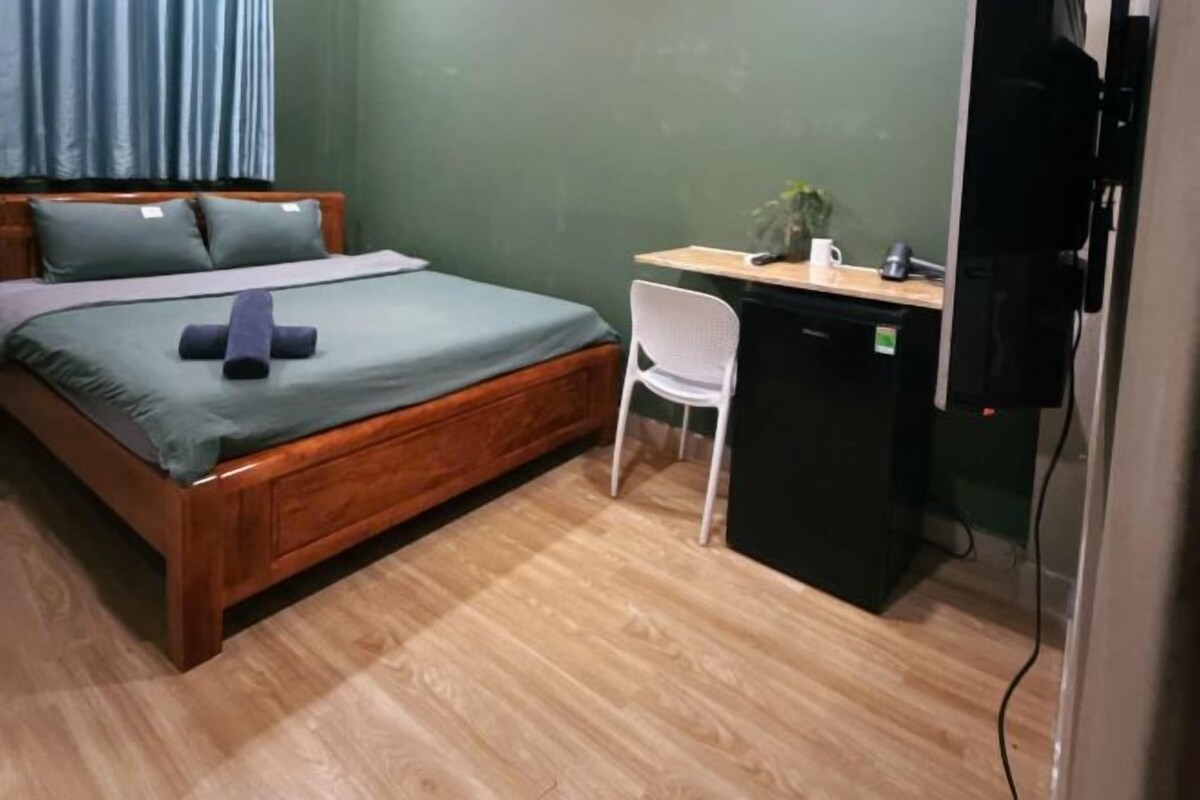 Une chambre à coucher avec un lit en bois, un bureau, une chaise et un téléviseur.