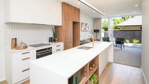 Una cocina moderna con armarios blancos, una pared de acento de madera y una isla grande con pileta.