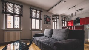 A modern living room with a sofa, a glass coffee table, and wooden flooring.