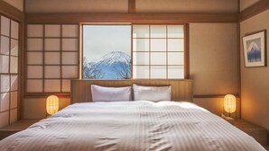 Habitació d'hotel amb un llit gran, vista a una muntanya, panells shoji i un quadre al mur.