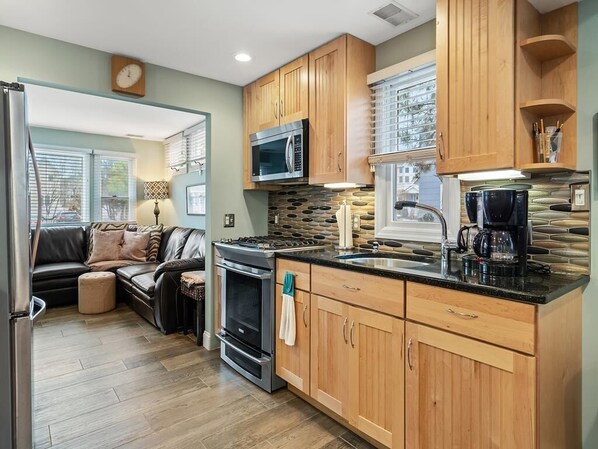 A compact kitchen with wooden cabinets, a stove, a microwave, and a coffee maker.