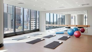 A spacious room with large windows, exercise mats, and exercise balls.
