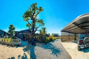 A tree-lined driveway leading to a building with a covered parking area and a vehicle parked inside. - Baanmax Boutique Pet Resort & Lodge, Chiangrai (Chiang Rai)