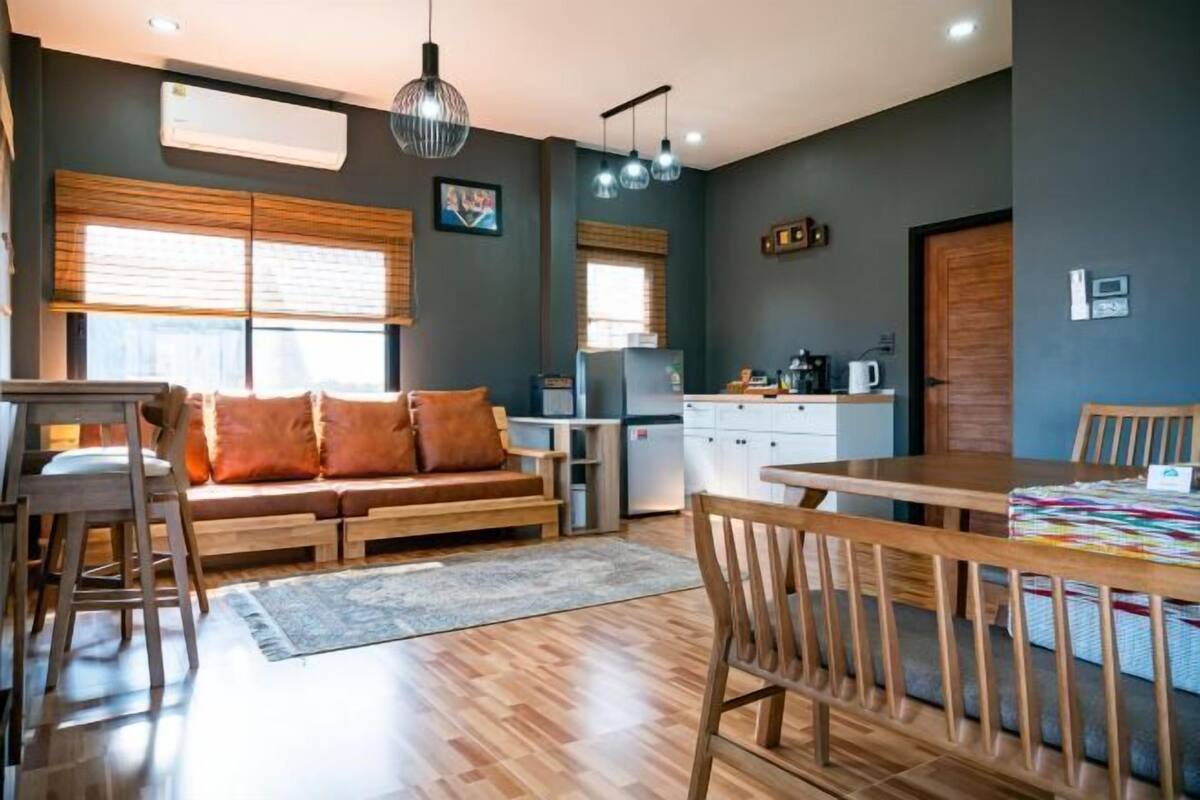 A modern kitchen with wooden cabinets, a dining table, and a sofa with cushions.