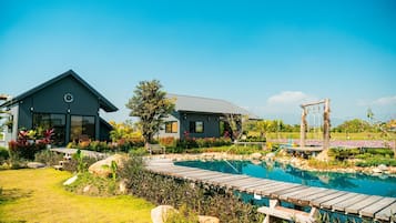 A modern house with a swimming pool, surrounded by a garden and a wooden deck.