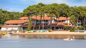 A coastal hotel with multiple balconies, a beachside location, and a row of colorful boats on the shore. - Sowell Family Pignada Plage by Interhome (Soustons)