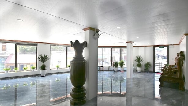 Un hall d’entrée spacieux agrémenté d’un grand vase décoratif, de plantes en pot et d’une statue.