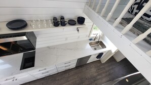 A compact kitchen with white cabinetry, a stainless steel sink, and a black stove.