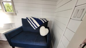 A dark blue sofa with a white heart-shaped pillow and a blue and white striped blanket.