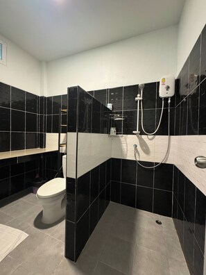 A modern bathroom with black and white tiled walls, a toilet, a shower area, and a towel rack.