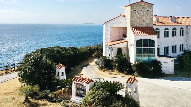 A coastal building with a white facade and red-tiled roof, overlooking the sea. - Tteuribada Pension (Seogwipo)