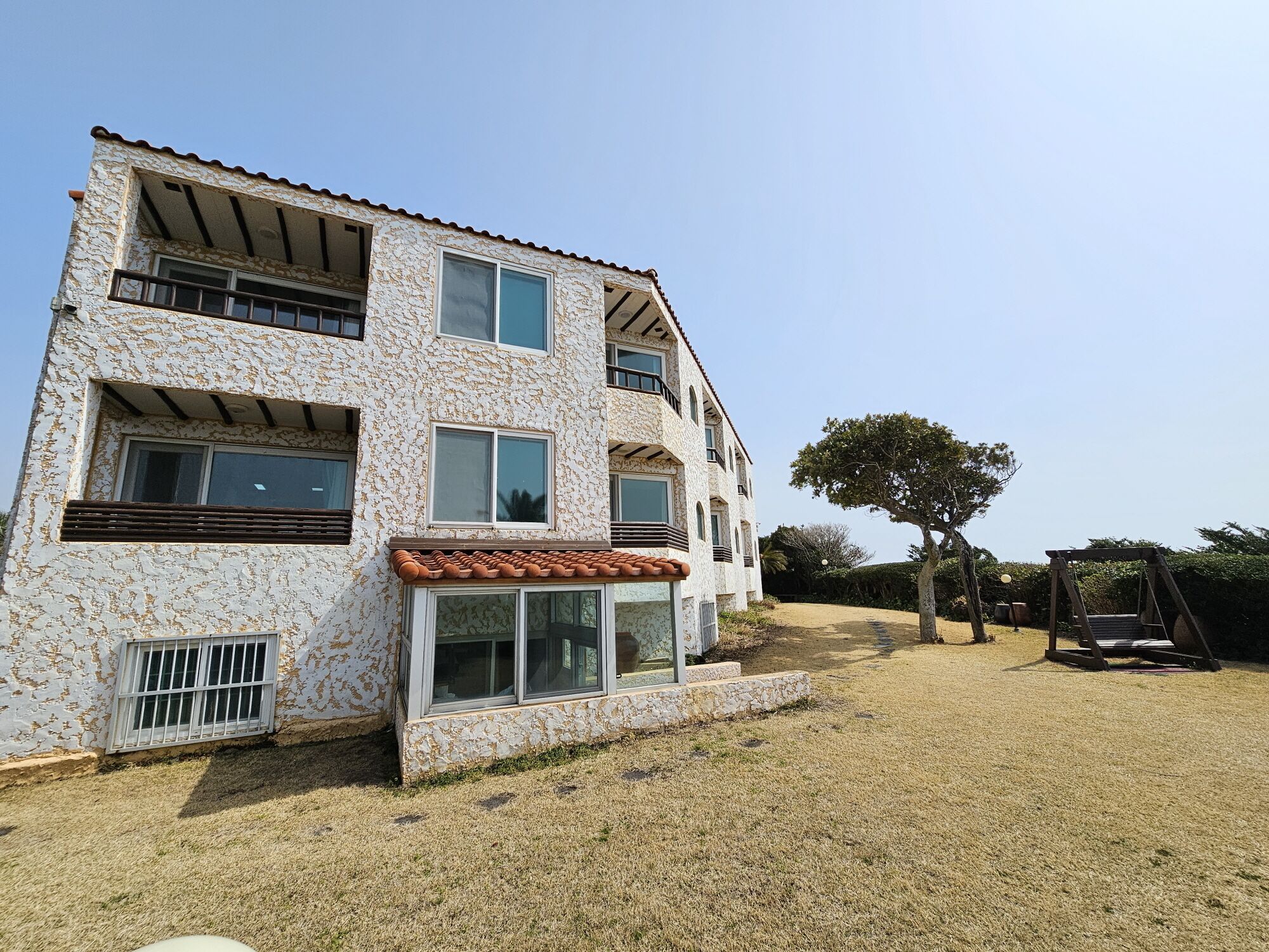 A two-story building with a stone facade, large windows, and a small patio area.