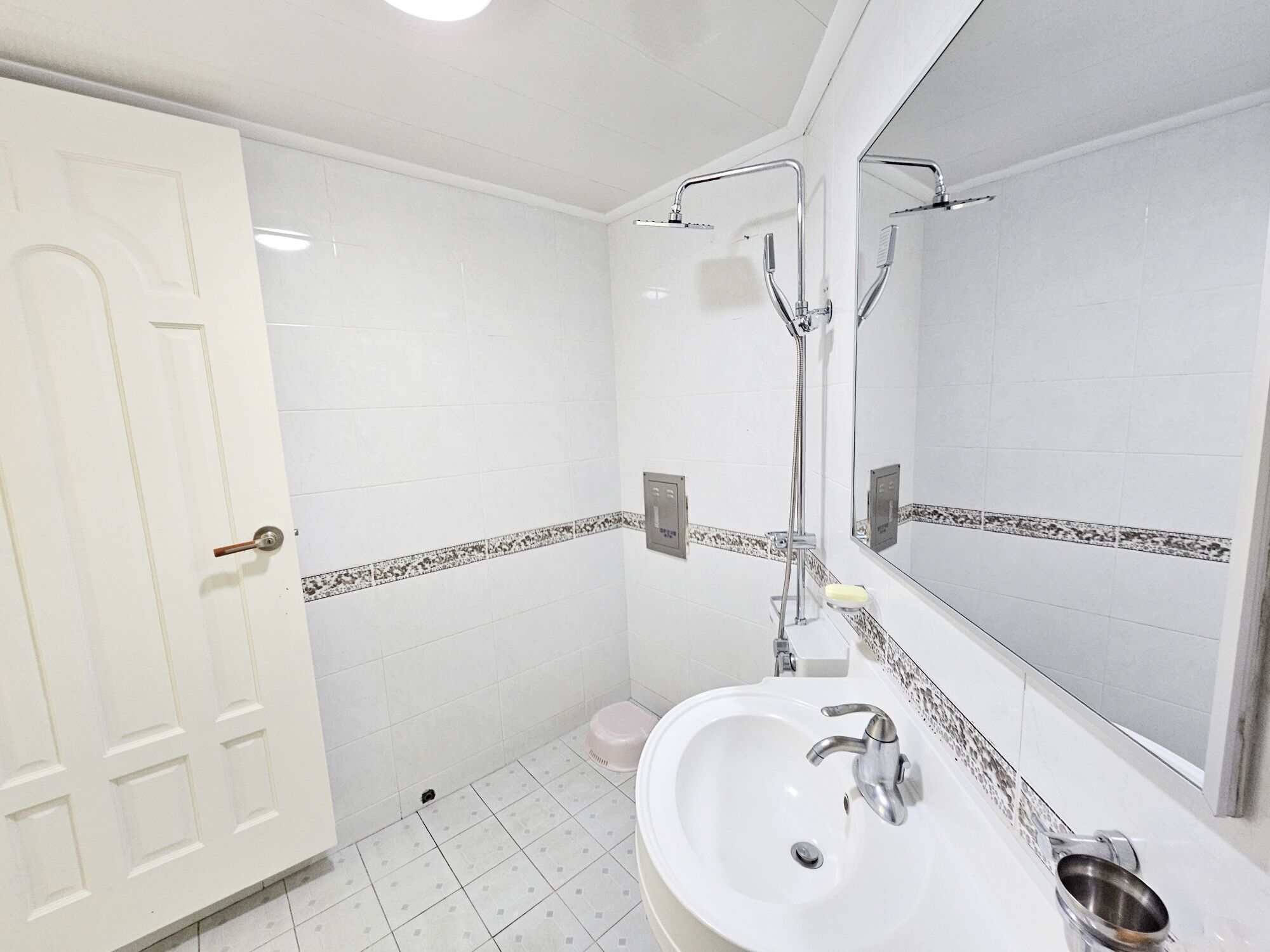 A bathroom with a white sink, a mirror, and a shower.